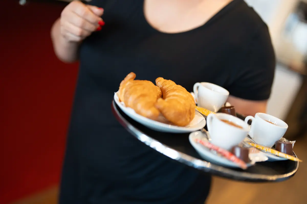 Ein Tablett mit Kaffee und Croissants wird serviert