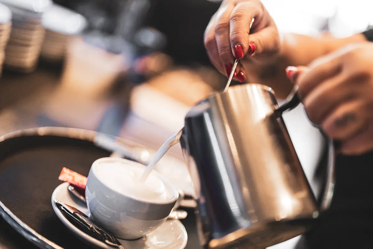 Milchschaum wird in eine Tasse gegossen