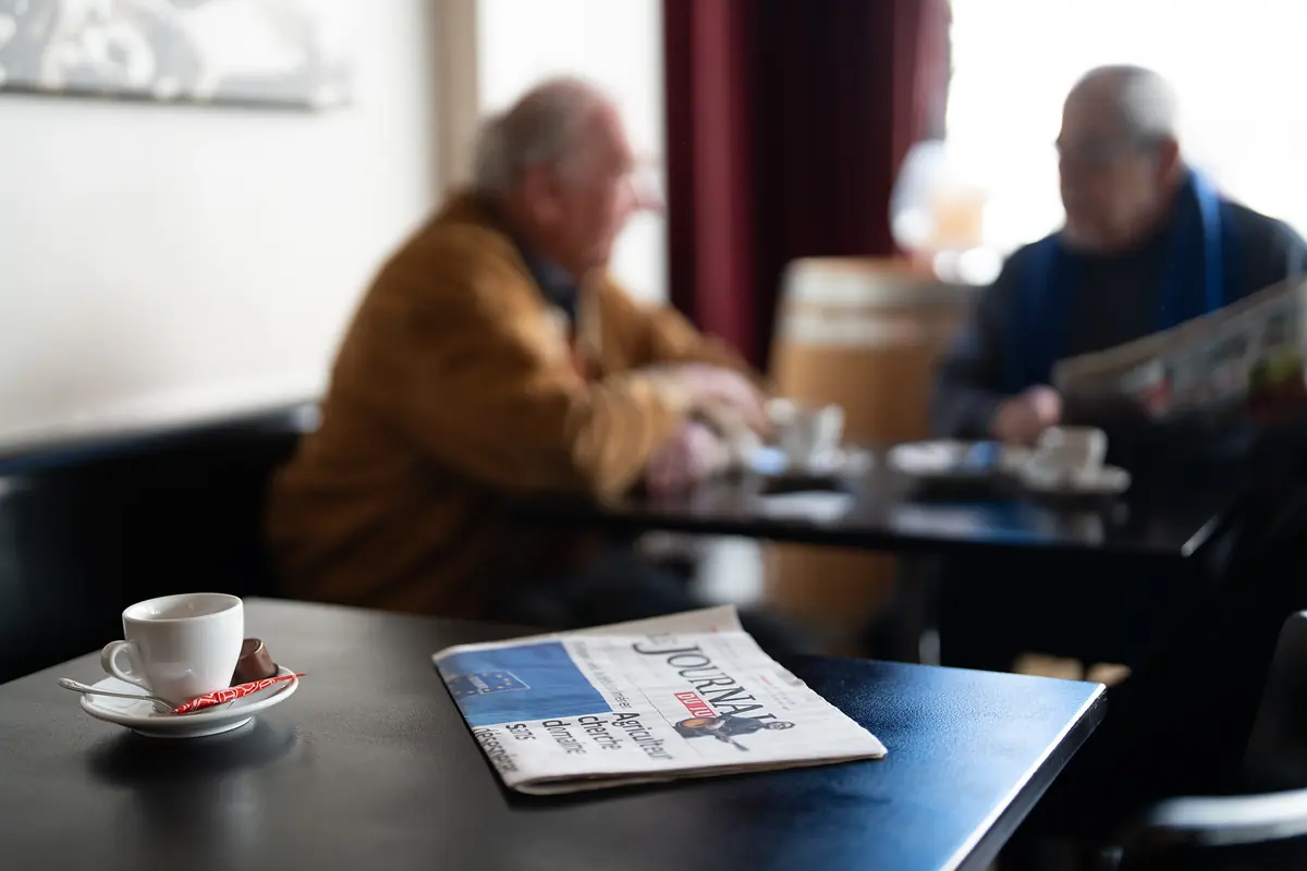 Ein Gast liest Zeitung bei einem Espresso