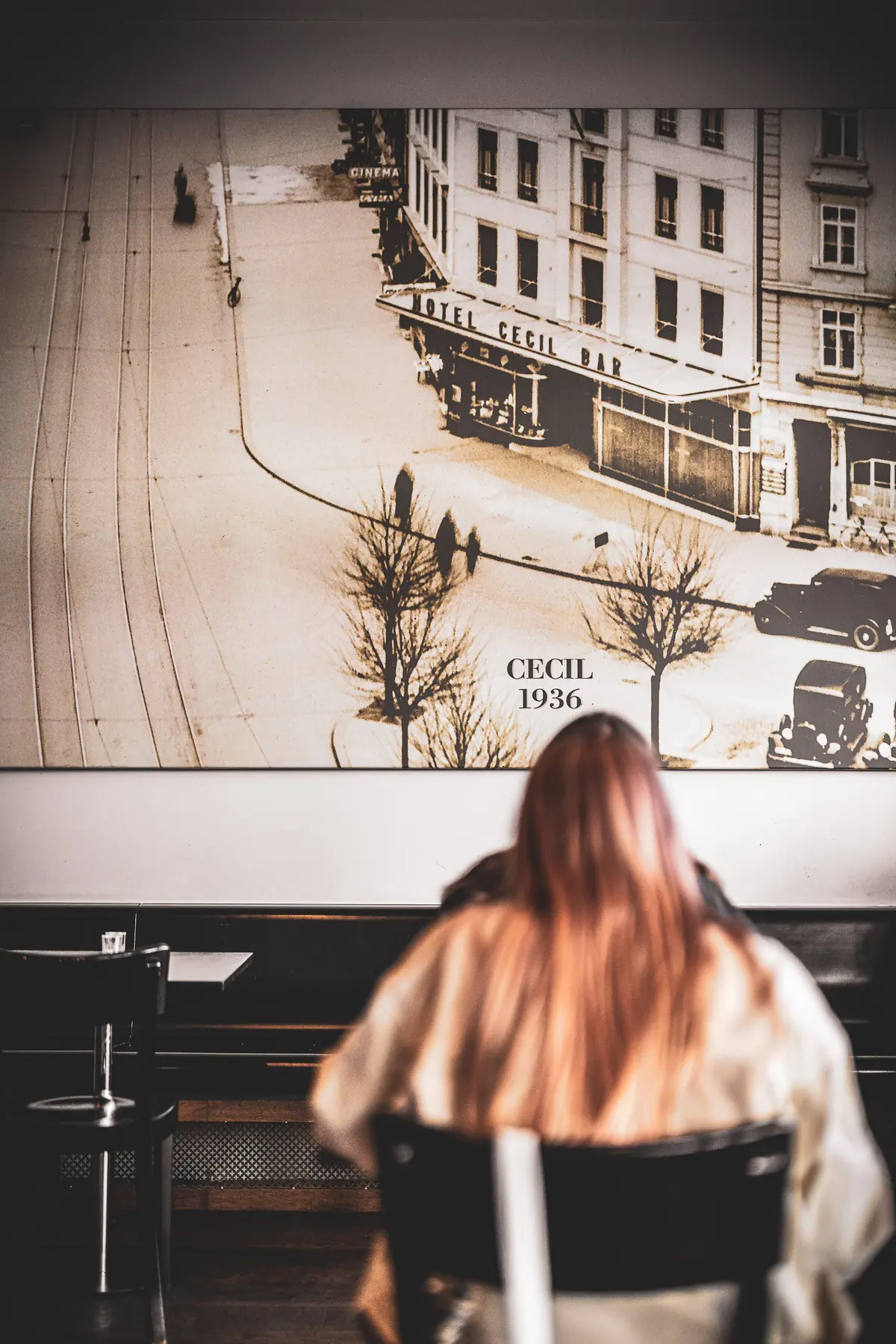 Ein Gast sitzt vor dem grossen Wandbild der «Hotel Cecil Bar» von 1936